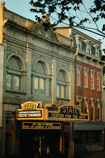 Black and white photograph of the Orpheum Theatre marquee with large, illuminated cursive lettering spelling 'Orpheum' at the top. Below, a white message board displays upcoming event dates and perfor